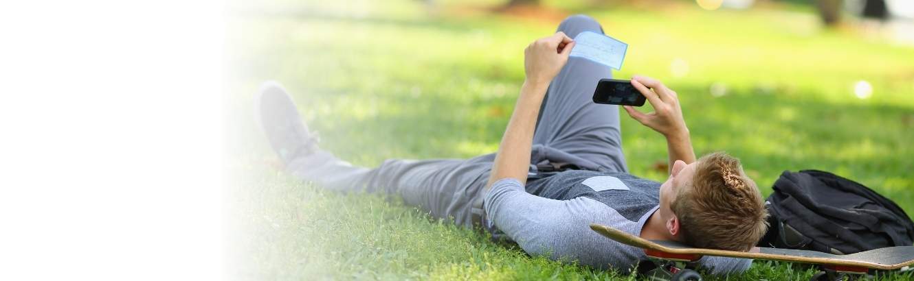 Image of a guy laying in the grass making a Mobile Deposit