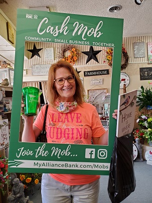 Woman hold green glass behind cash mob frame